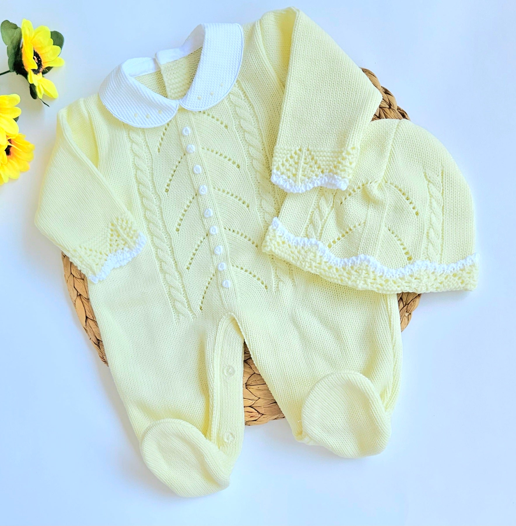A yellow knitted baby romper with handmade embroidery, accompanied by a matching hat, displayed on a basket. Newborn Going home set