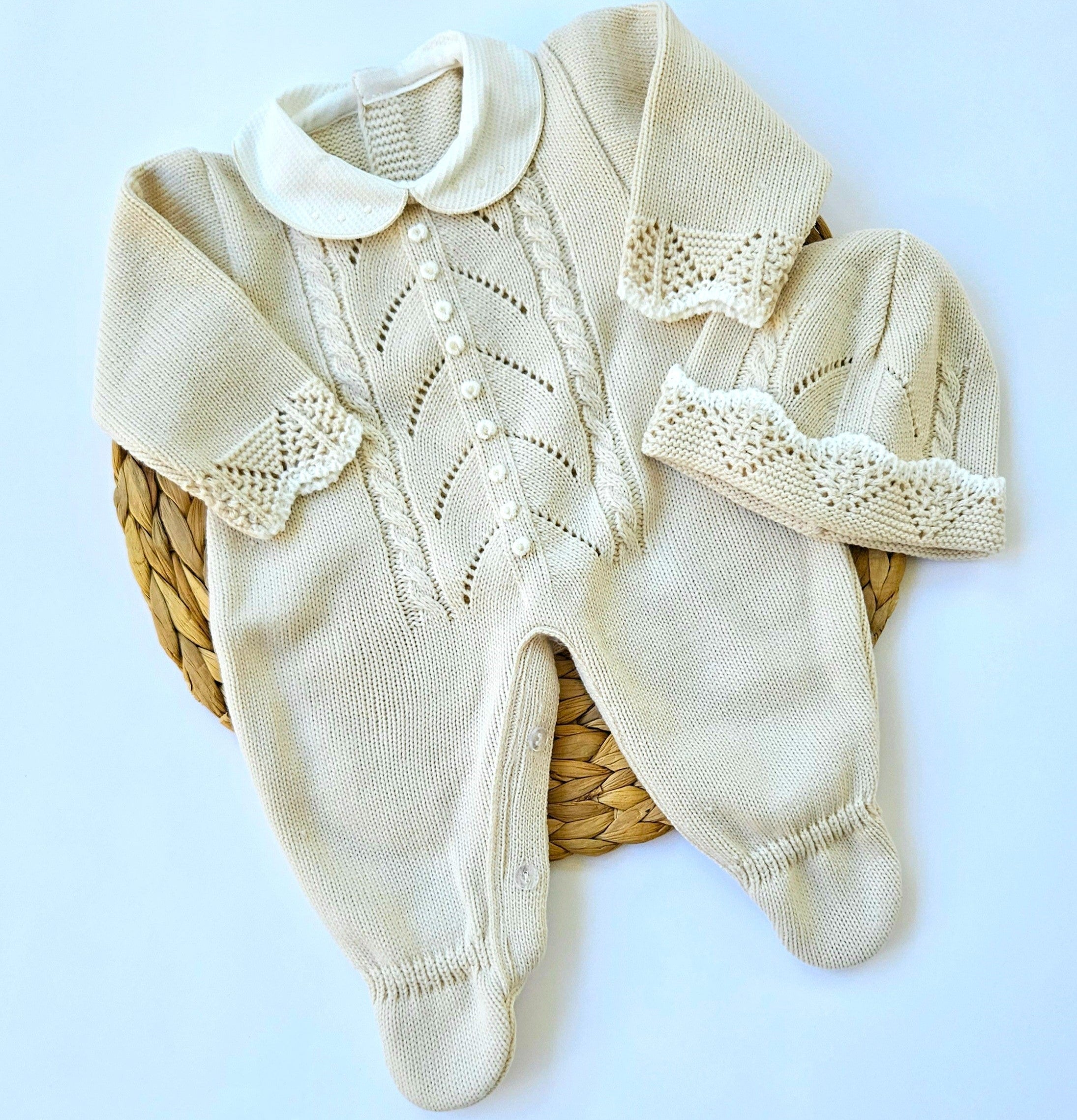 A beige and white knitted romper for babies with handmade rococo embroidery, displayed on a white background.