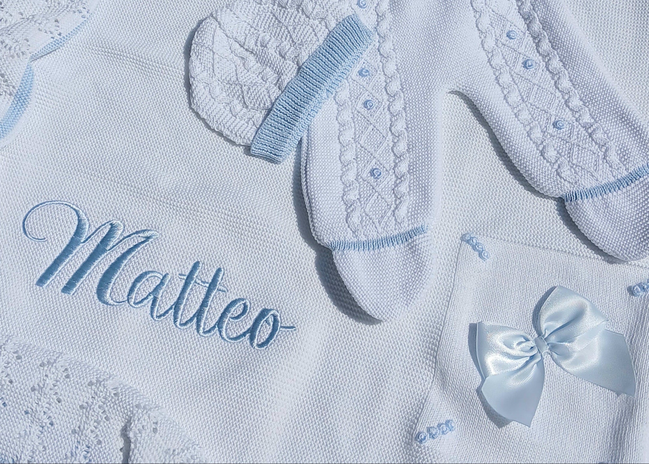 Baby outfit set with embroidered name 'Matteo' on a textured fabric background