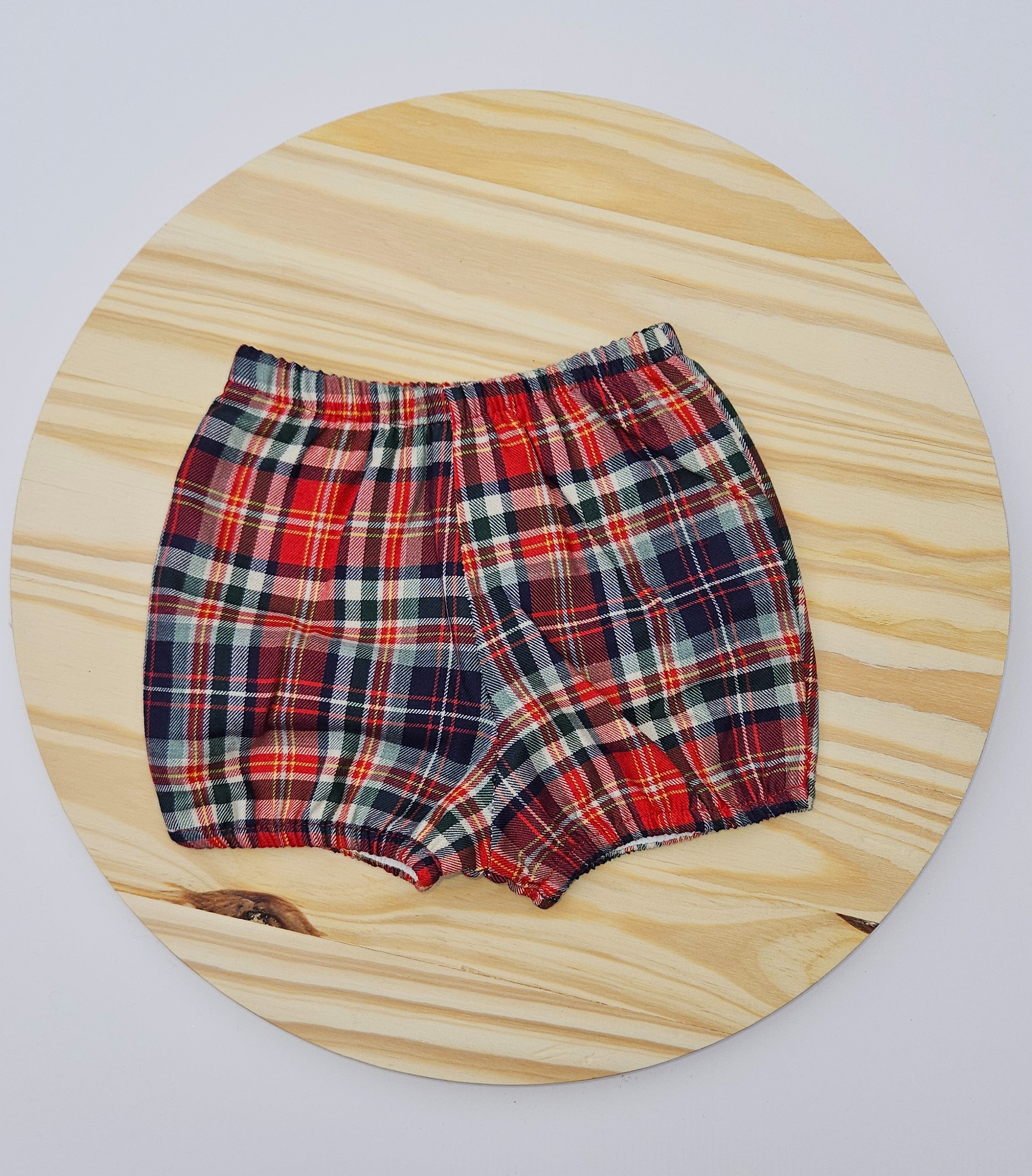 Plaid baby bloomers on a wooden board with a white background