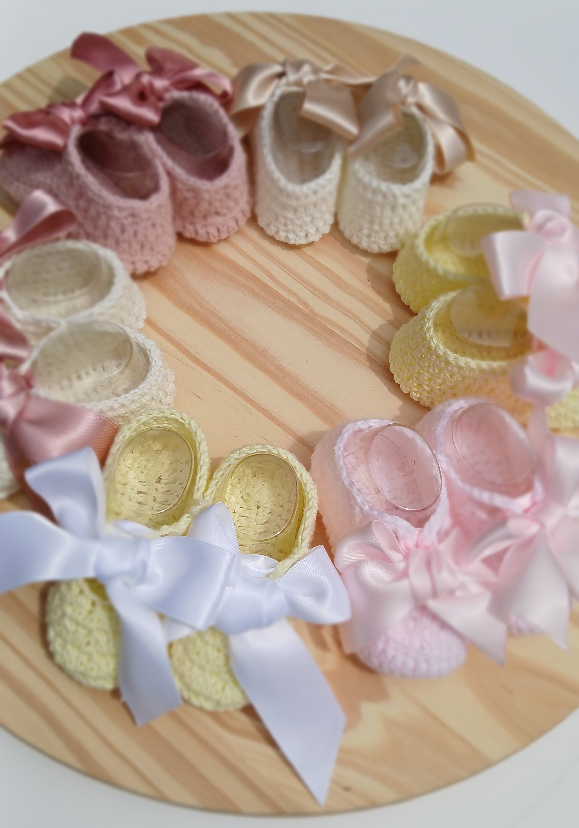 Decorative wreath with baby shoes and booties on a wooden board baby Bootie crochet yellow with satin bow