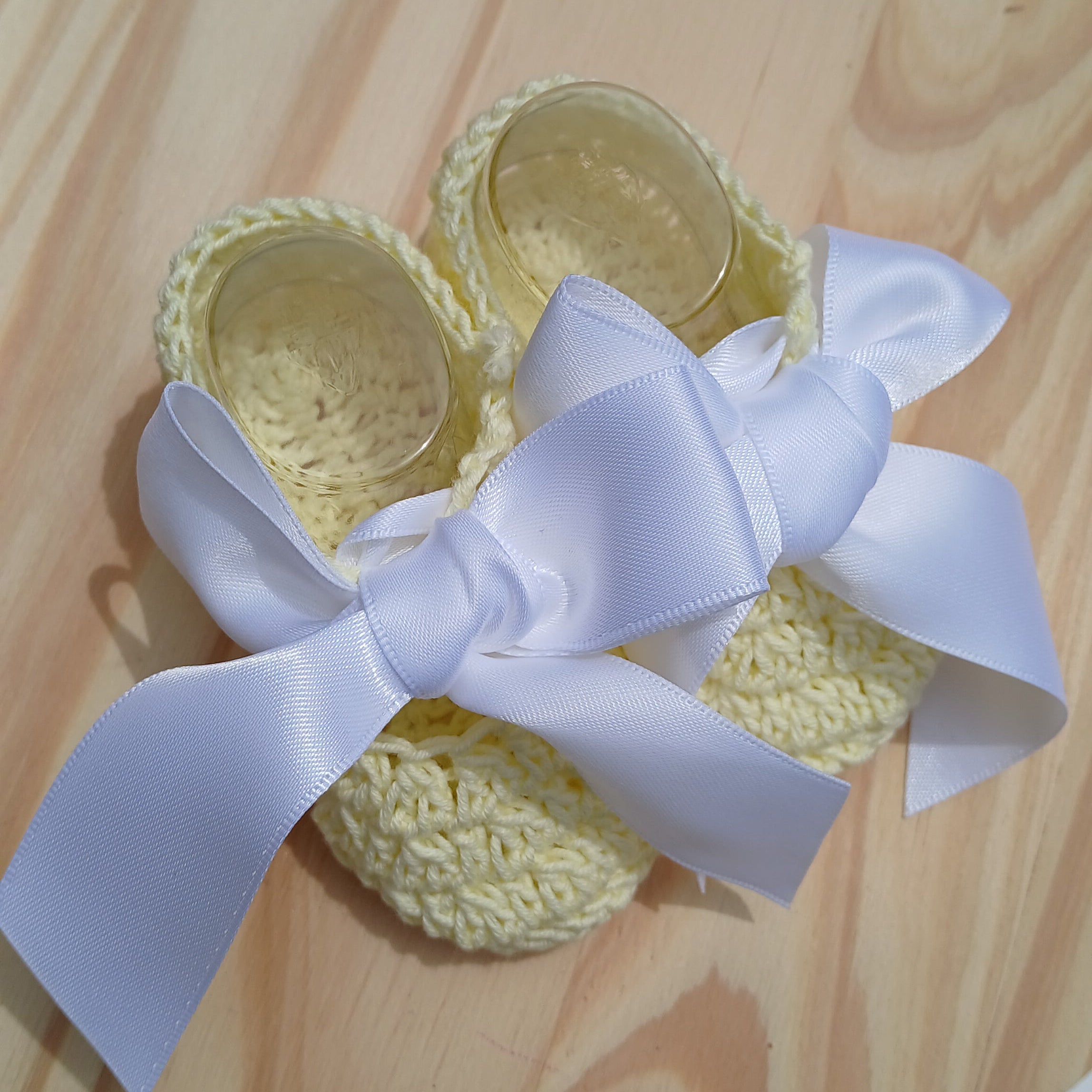 Yellow baby shoes with a white bow on a wooden surface baby Bootie crochet yellow with satin bow