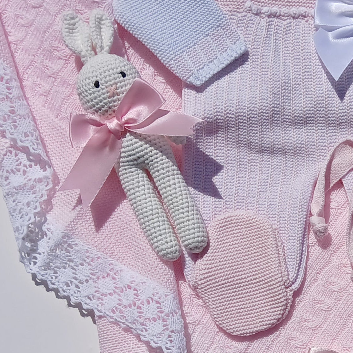 Pink baby outfit with bow details on a white surface