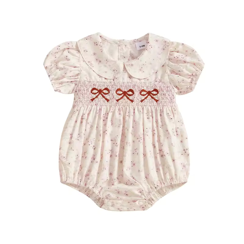 Baby romper with ruffled collar and embroidered bows on a white background