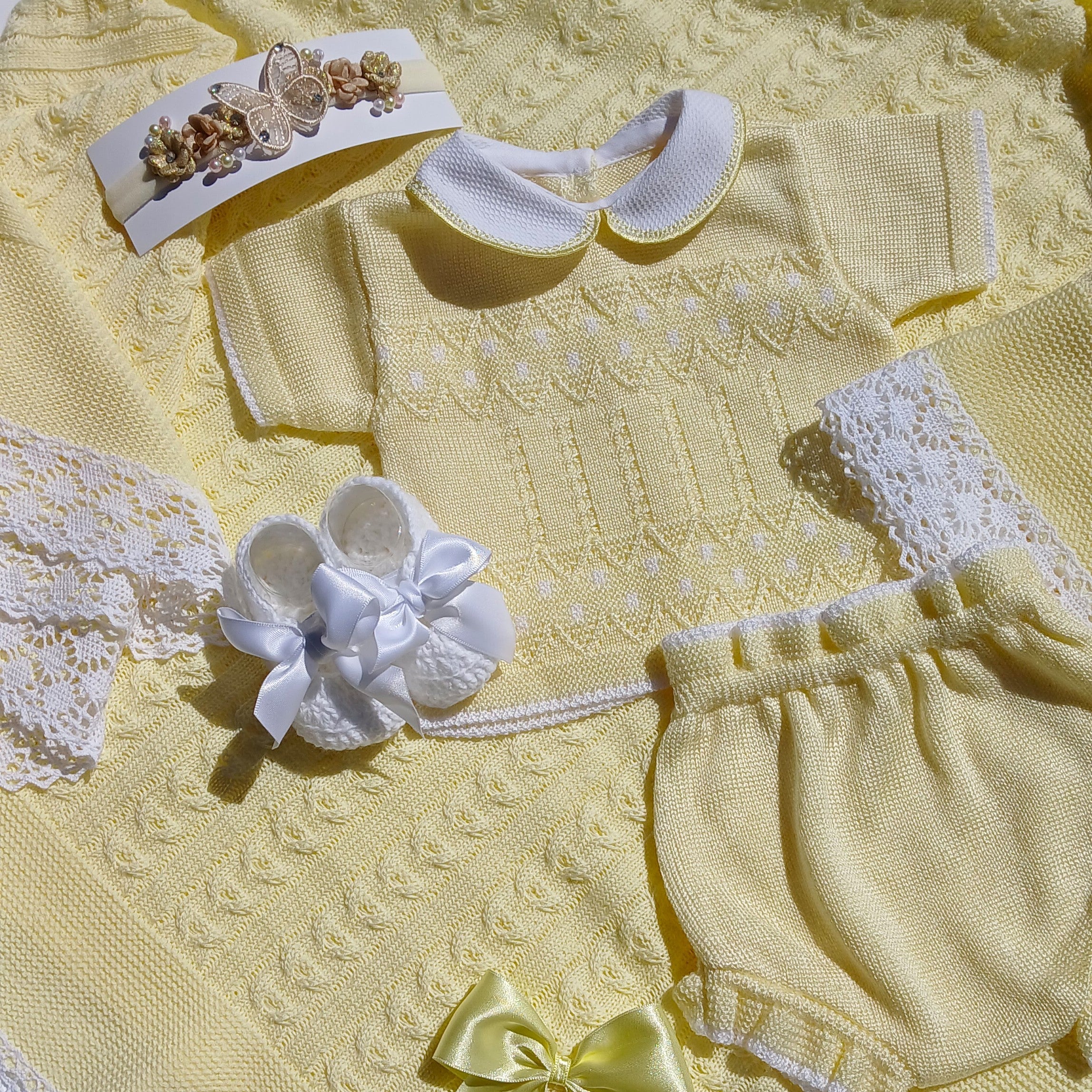 Yellow summer baby outfit with matching butterfly headband and white bootie w a bow, yellow knit baby blanket Yellow baby outfit with matching headband and bow on a textured surface