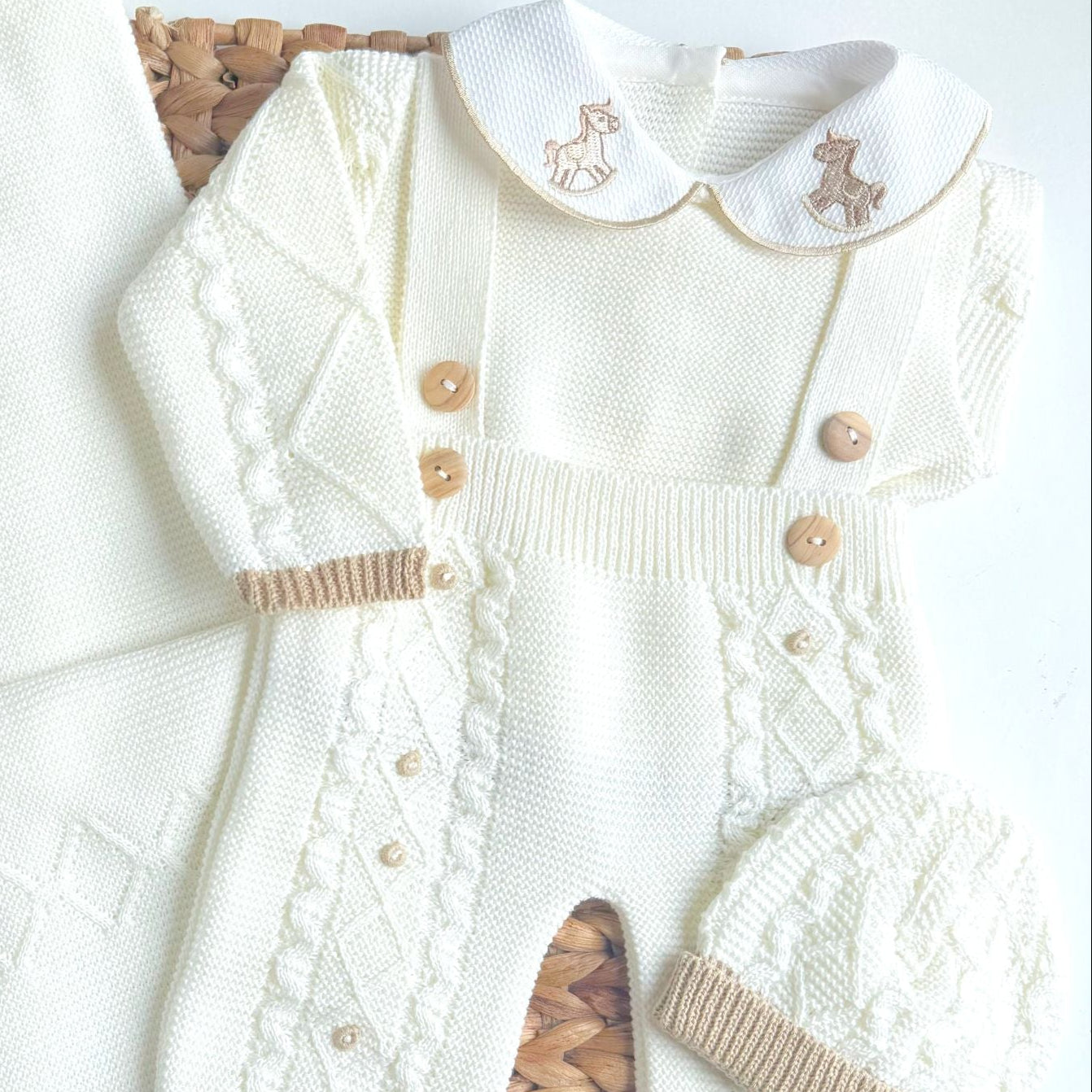 White baby outfit with embroidered details on a white background
Newborn knit outfit for baby coming home from hospital, rocking horse embroidery on the collar of the outfit, and baby's name embroidery