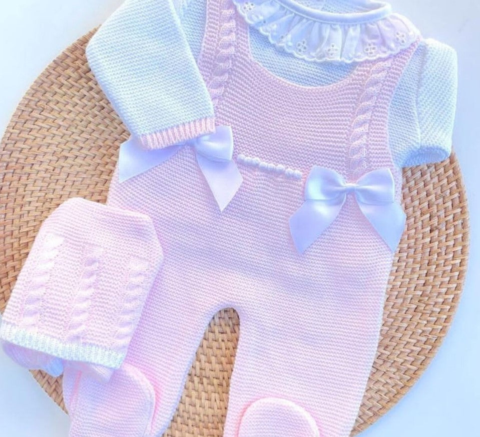 Baby outfit with pink romper and white sleeves on a woven surface