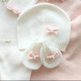 White baby outfit with pink bows on a pink blanket