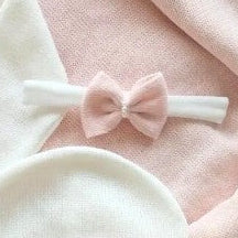 White baby outfit with pink bows on a pink blanket