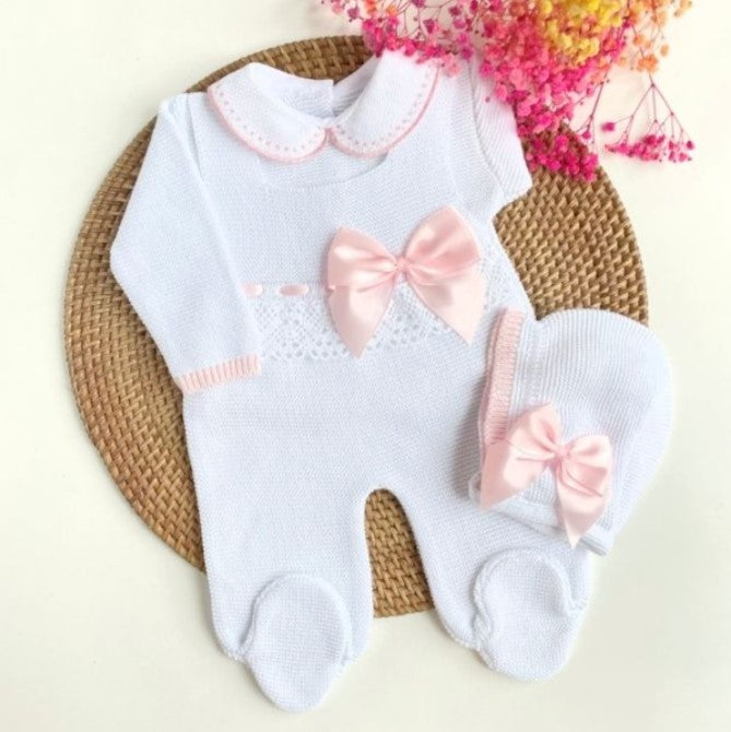 Baby outfit with pink bows on a woven mat
