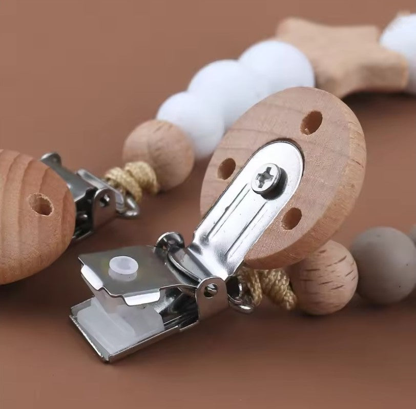 Wooden baby rattle with metal clip on a brown background star pacifier chain, teething silicone beads, silicone beads baby pacifier chain clip