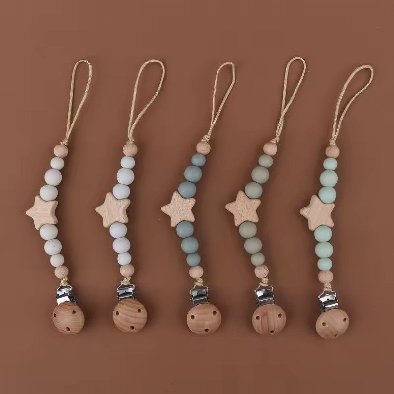 star pacifier chain, teething silicone beads, silicone beads baby pacifier chain Set of five wooden pacifier clips with beads and star-shaped ends on a brown background