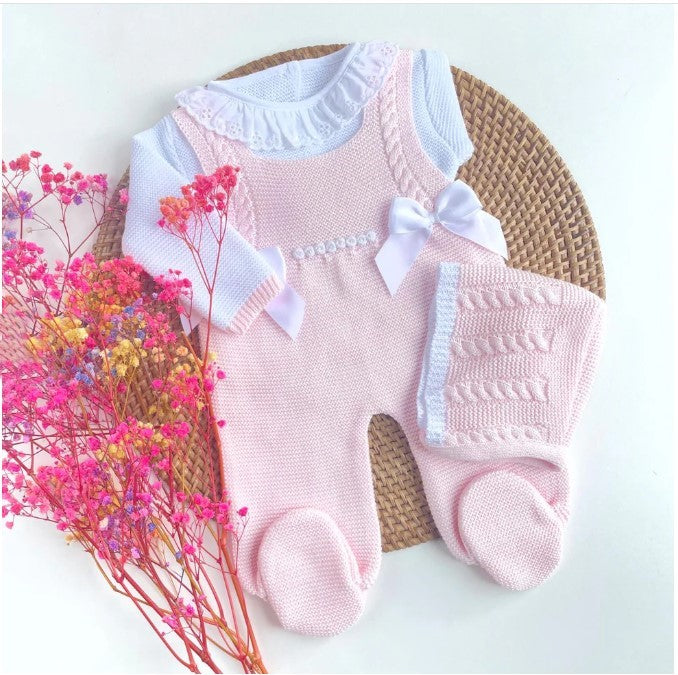 Pink knitted baby romper with white ruffled top on a light background