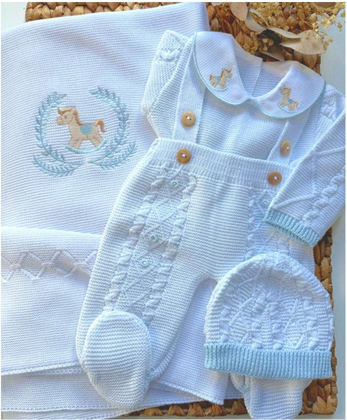 Baby outfit set with knitted romper, hat, and blanket featuring horse designs on a textured surface.