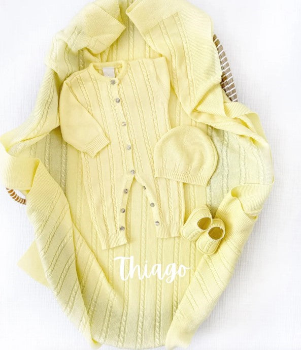 Yellow baby outfit with cardigan, hat, and booties on a white background
