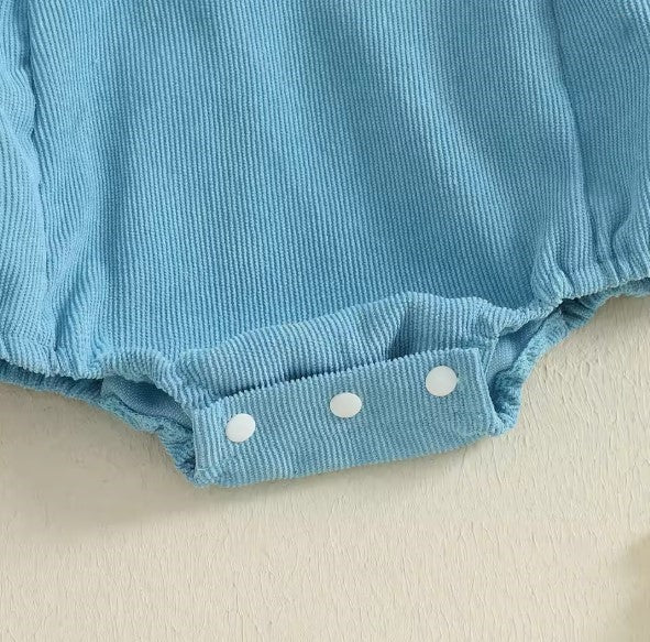 Blue baby bloomers with white polka dots on a beige surface