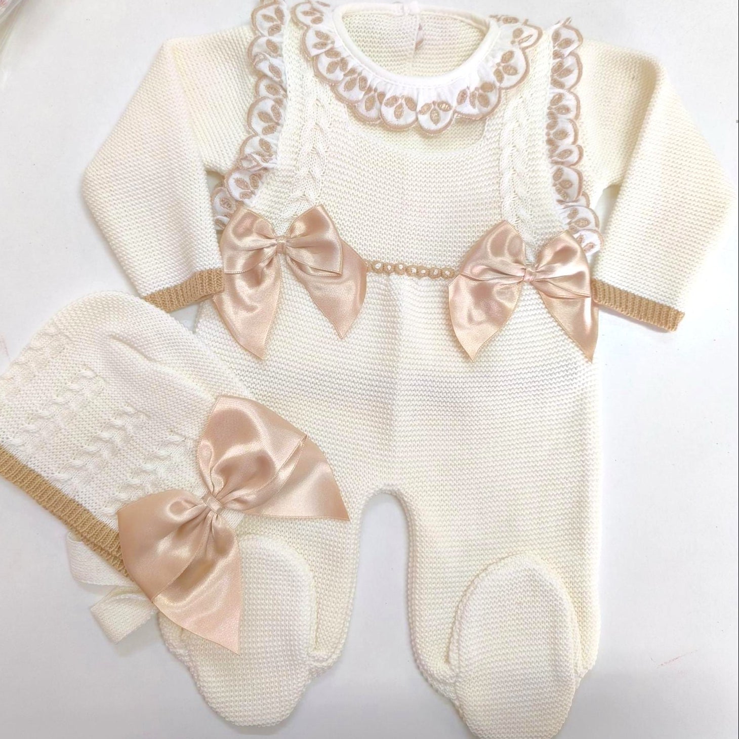 Baby romper with lace details and satin bows on a white background