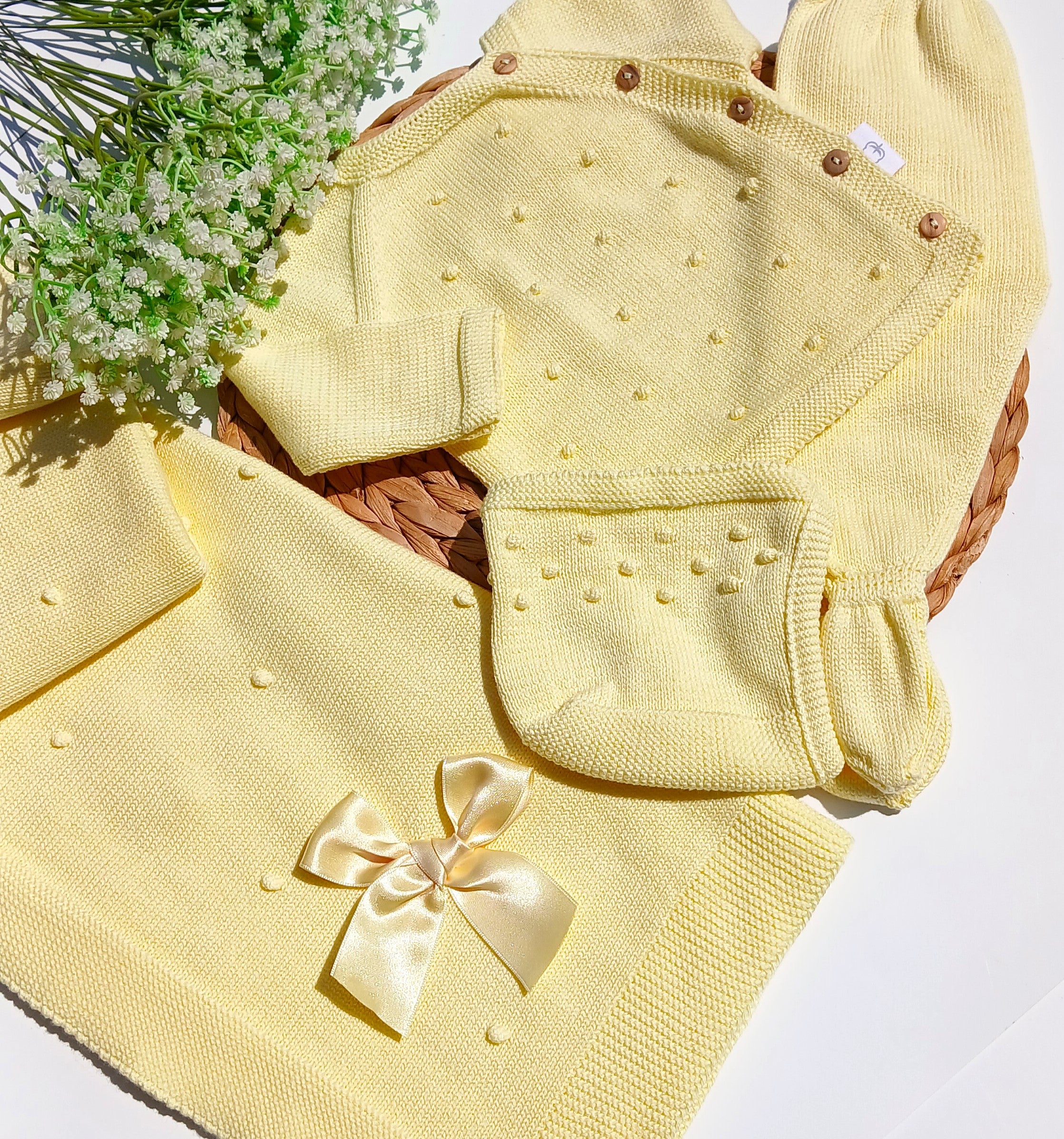 Yellow baby outfit with a bow and bib on a white background