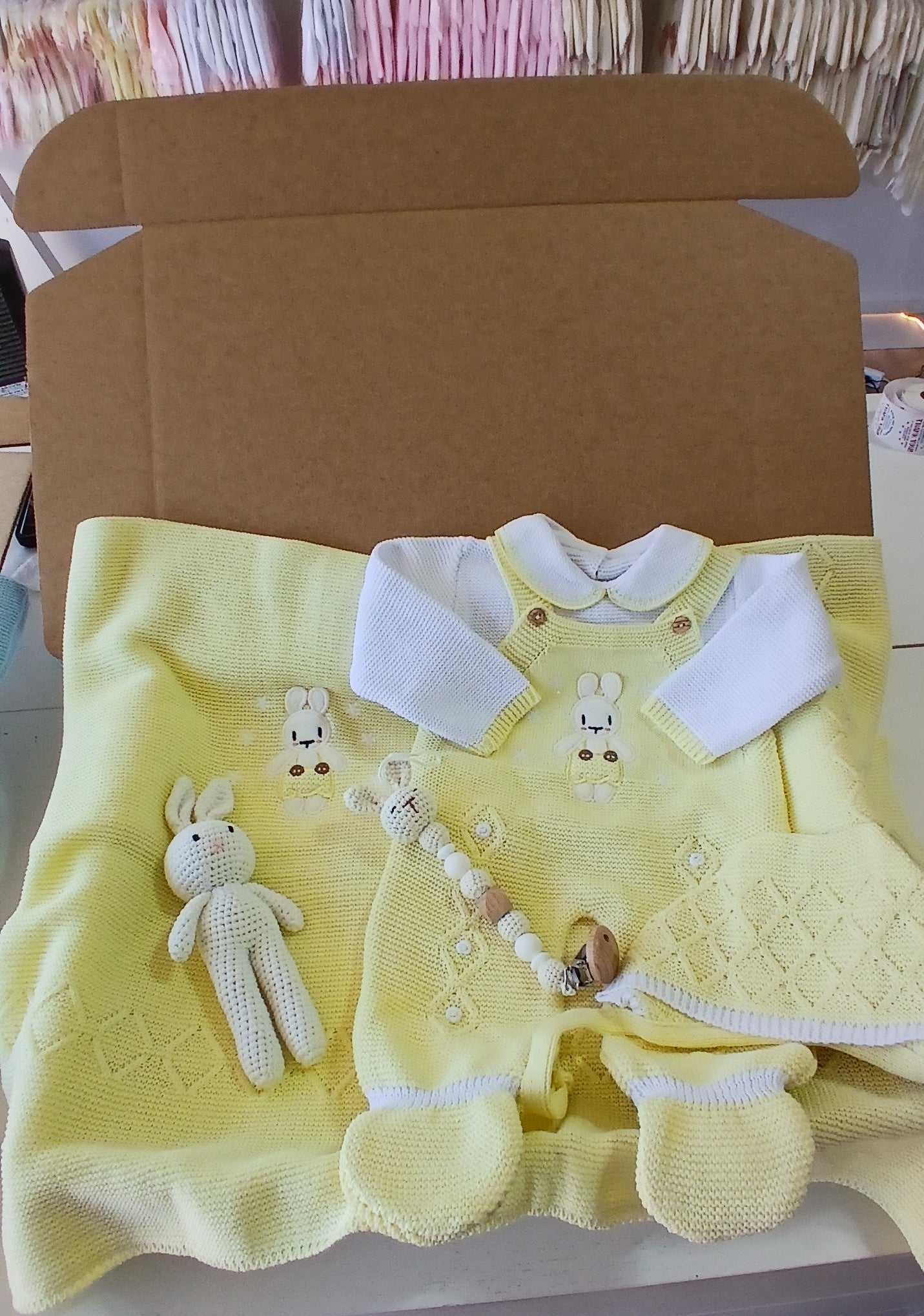 Yellow baby outfit with matching headband and booties in a cardboard box.