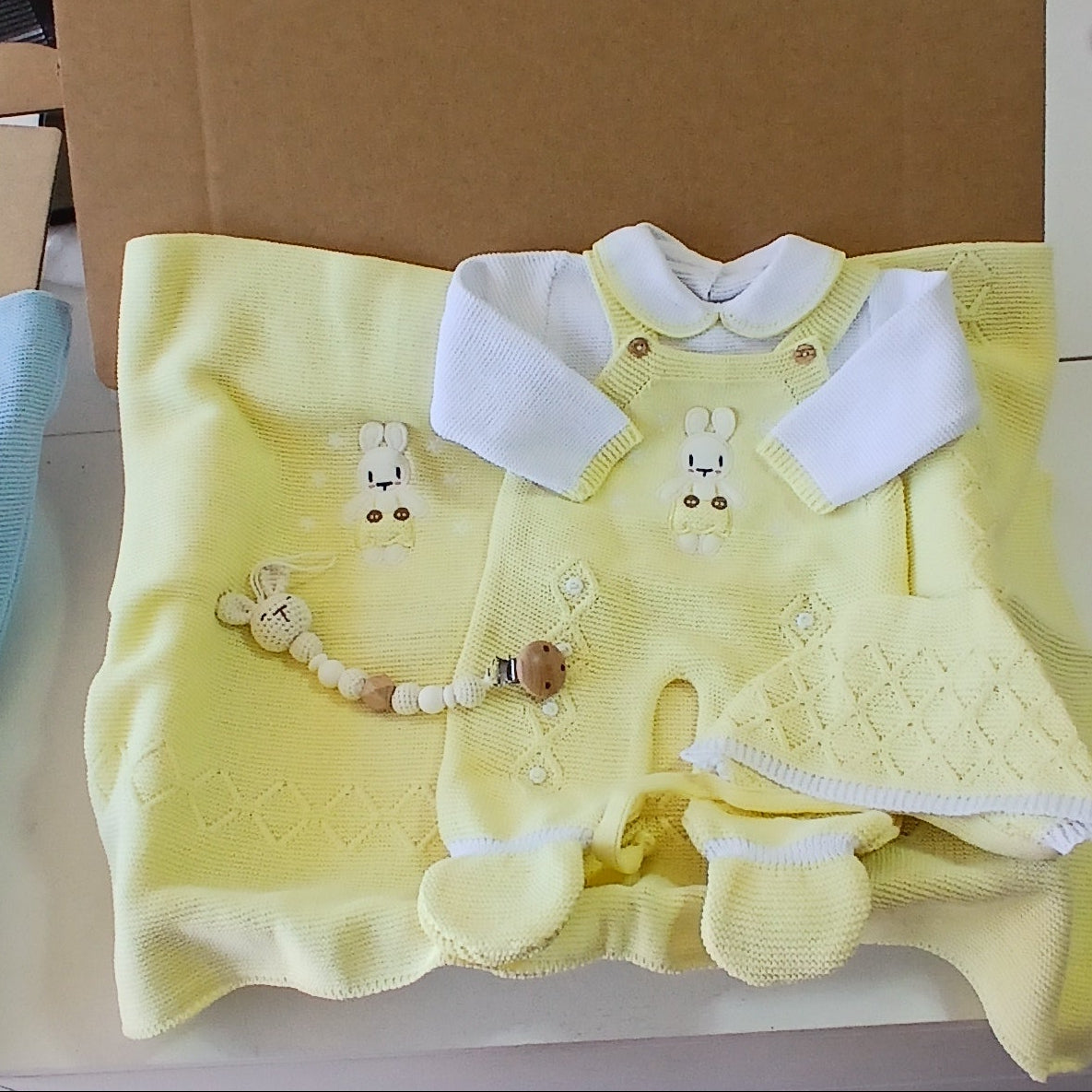 Yellow baby outfit with matching headband and booties in a cardboard box.