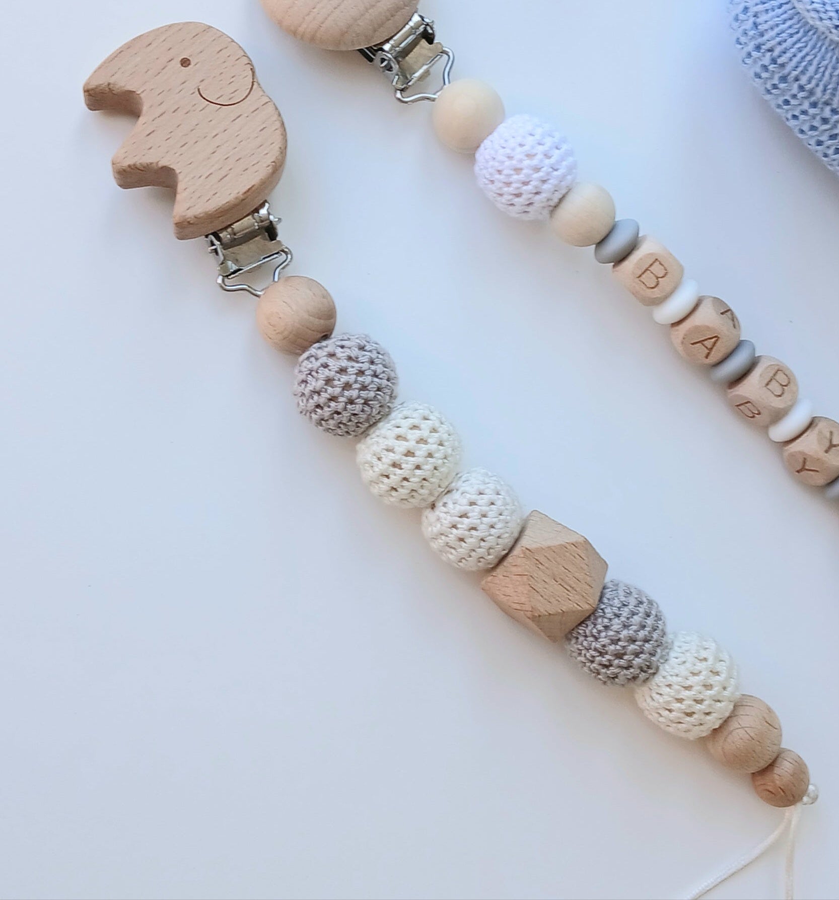 Wooden elephant crochet pacifier clip with beads and a small bag with teddy bear design on a white background