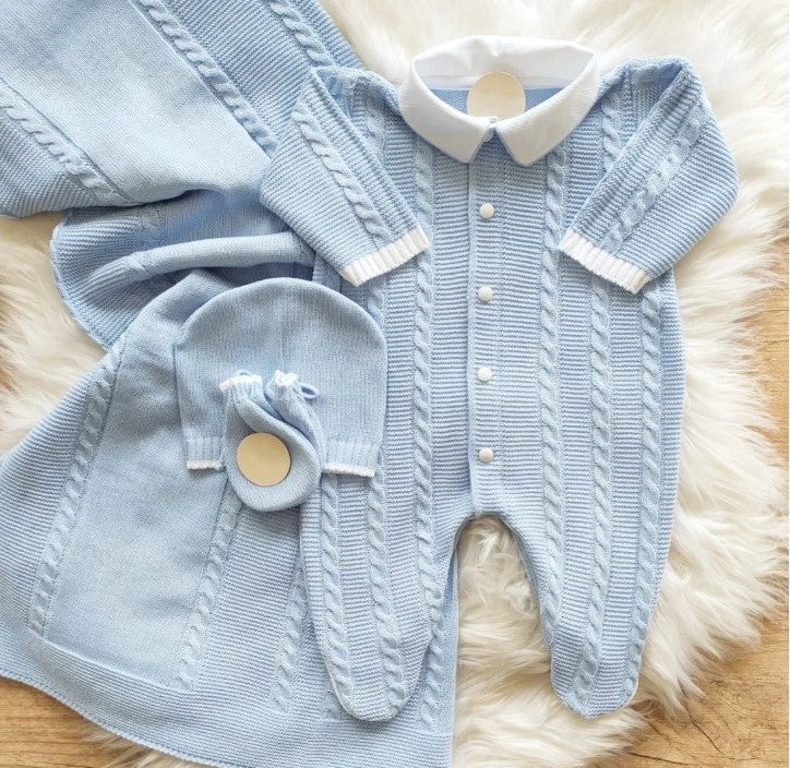 Knitted baby outfit with romper and hat on a fluffy surface