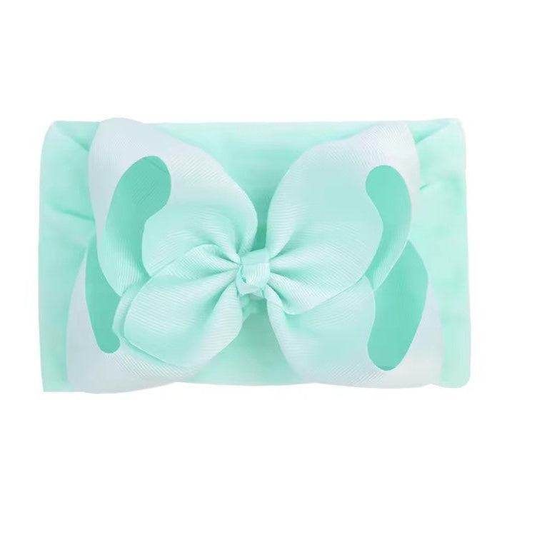 Mint green headband with a large bow on a white background