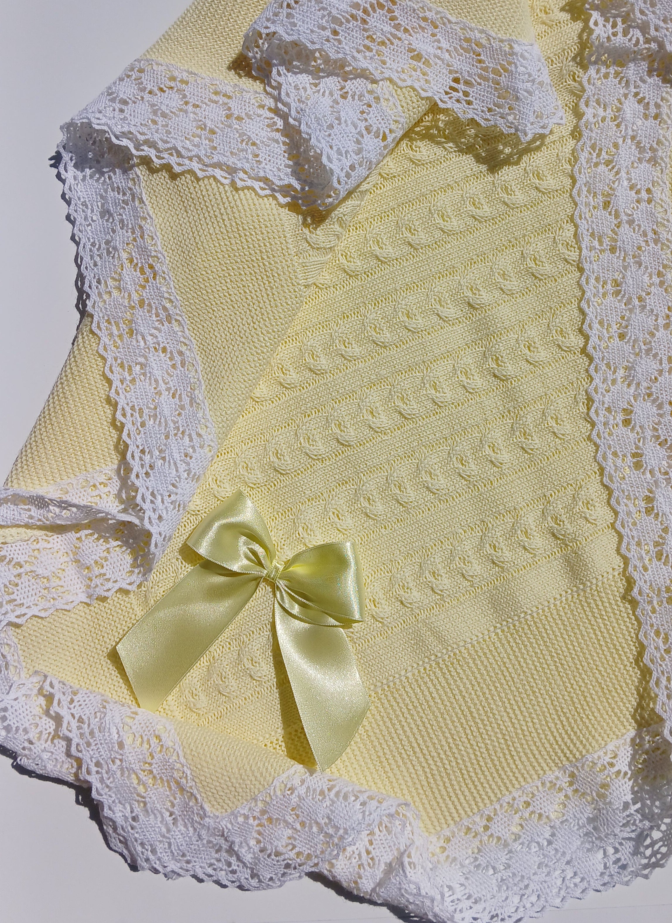 Yellow textured fabric with white lace trim and a yellow bow on a white background