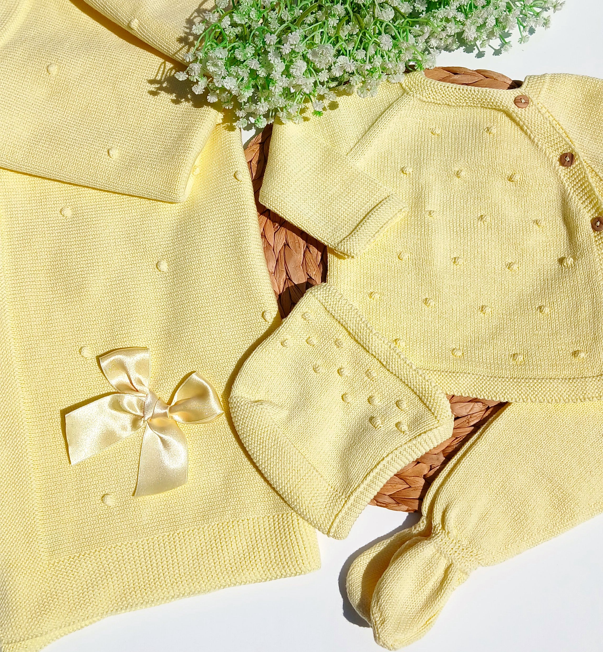 Yellow baby outfit with a bow and matching blanket on a white background