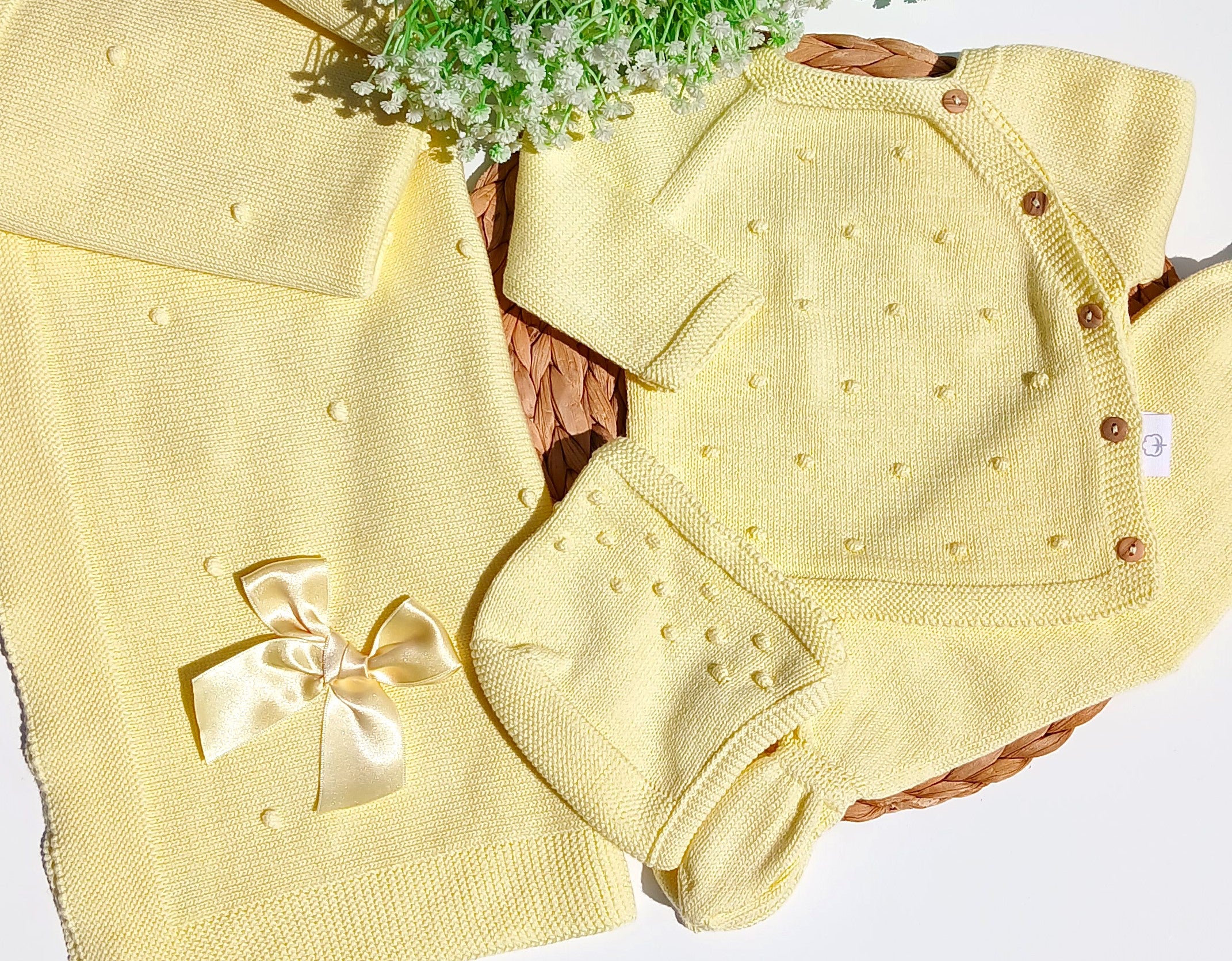 Yellow baby outfit with a bow and matching blanket on a white background