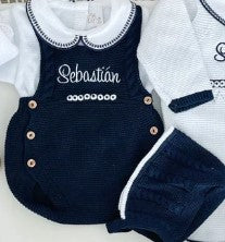 Navy blue romper with white trim and embroidered name on a light gray background
