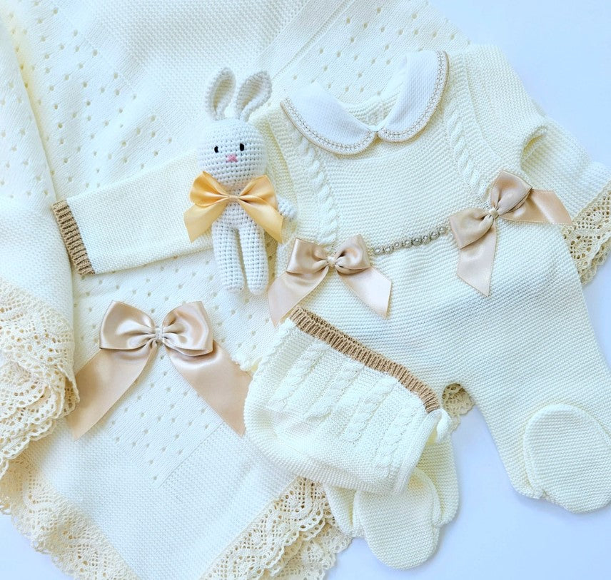 Collection of baby clothing and accessories with ribbons on a white background