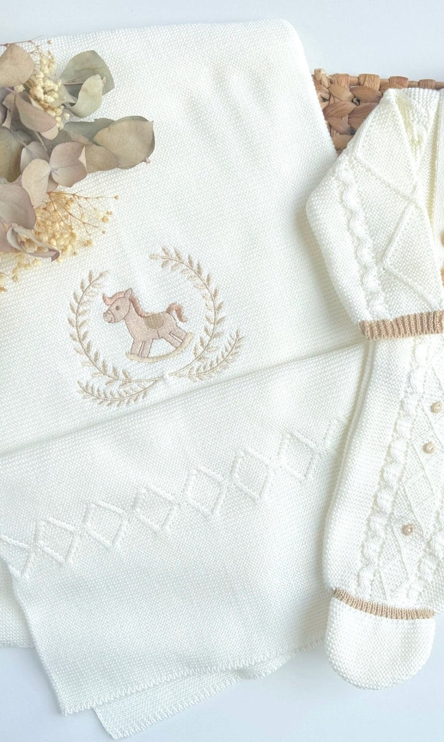 ivory baby blanket with embroidered horse design and matching booties on a light blue background Embroidered blanket with a horse design, baby blanket, and toy Newborn baby blanket