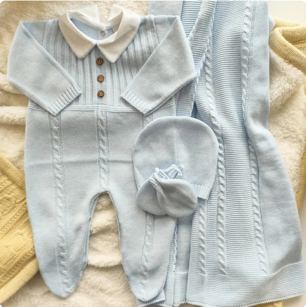 Light blue baby outfit with matching hat on a textured surface