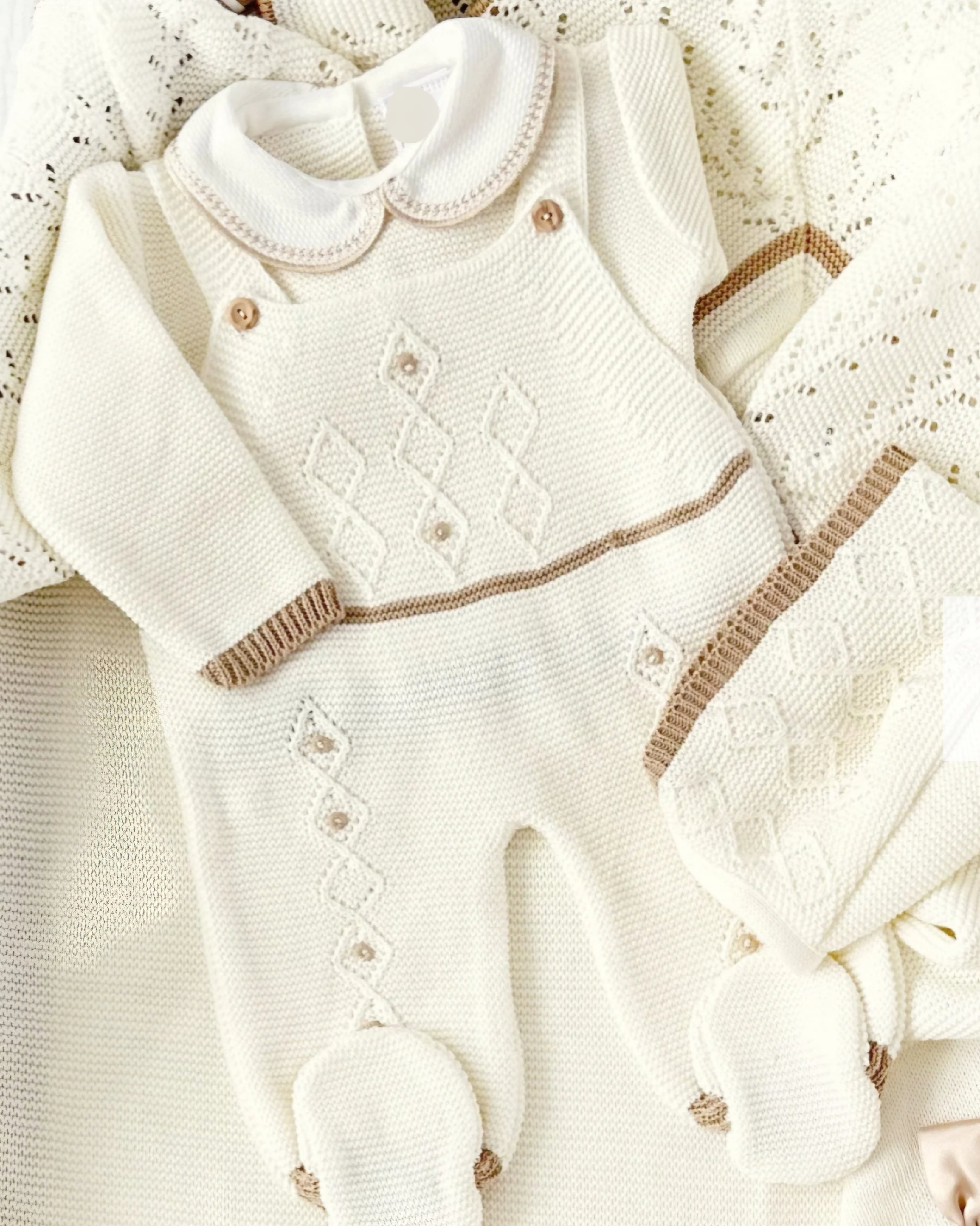 White baby romper with brown accents on a textured white background