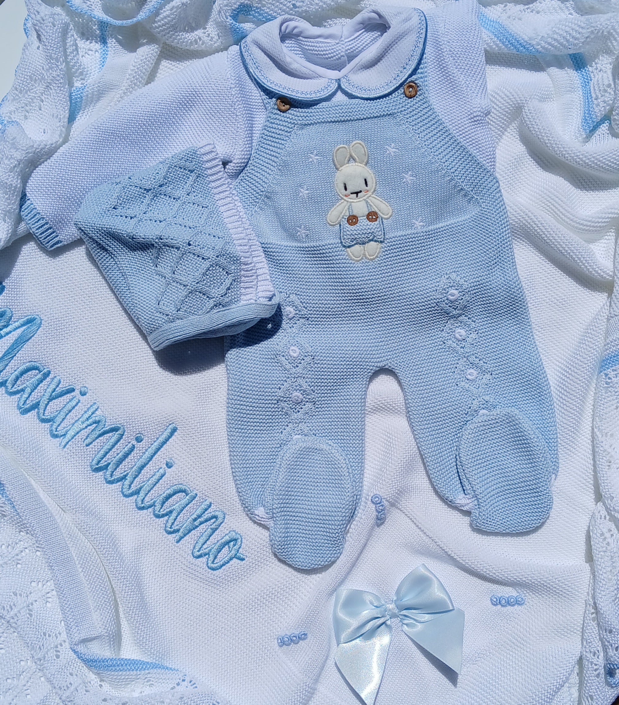 Blue baby outfit with embroidered bear design on a textured white background