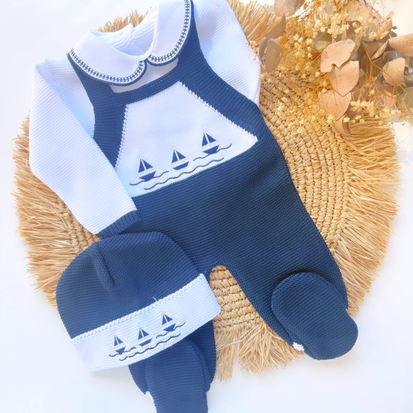 Blue and white baby outfit with sailboat design on a textured surface newborn sailor navy theme