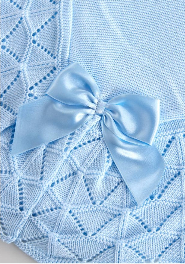 Blue knitted blanket with a large bow on a light blue background