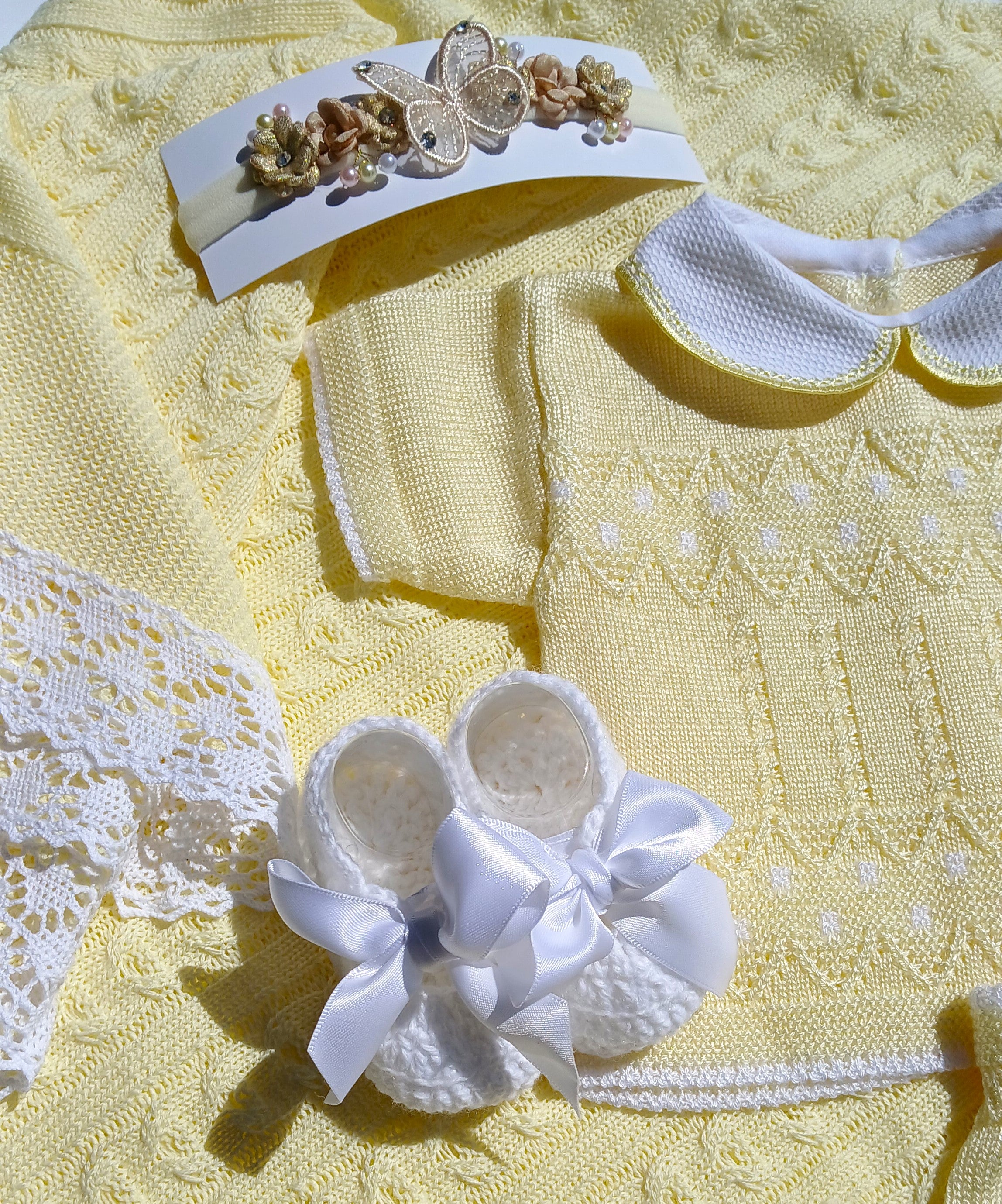 Yellow baby dress with white lace details and matching headband on a yellow textured background yellow knit baby outfit, summer with diaper cover baby white bootie butterfly headband yellow bloomer Yellow summer baby outfit with matching butterfly headband and white bootie w a bow, yellow knit baby blanket