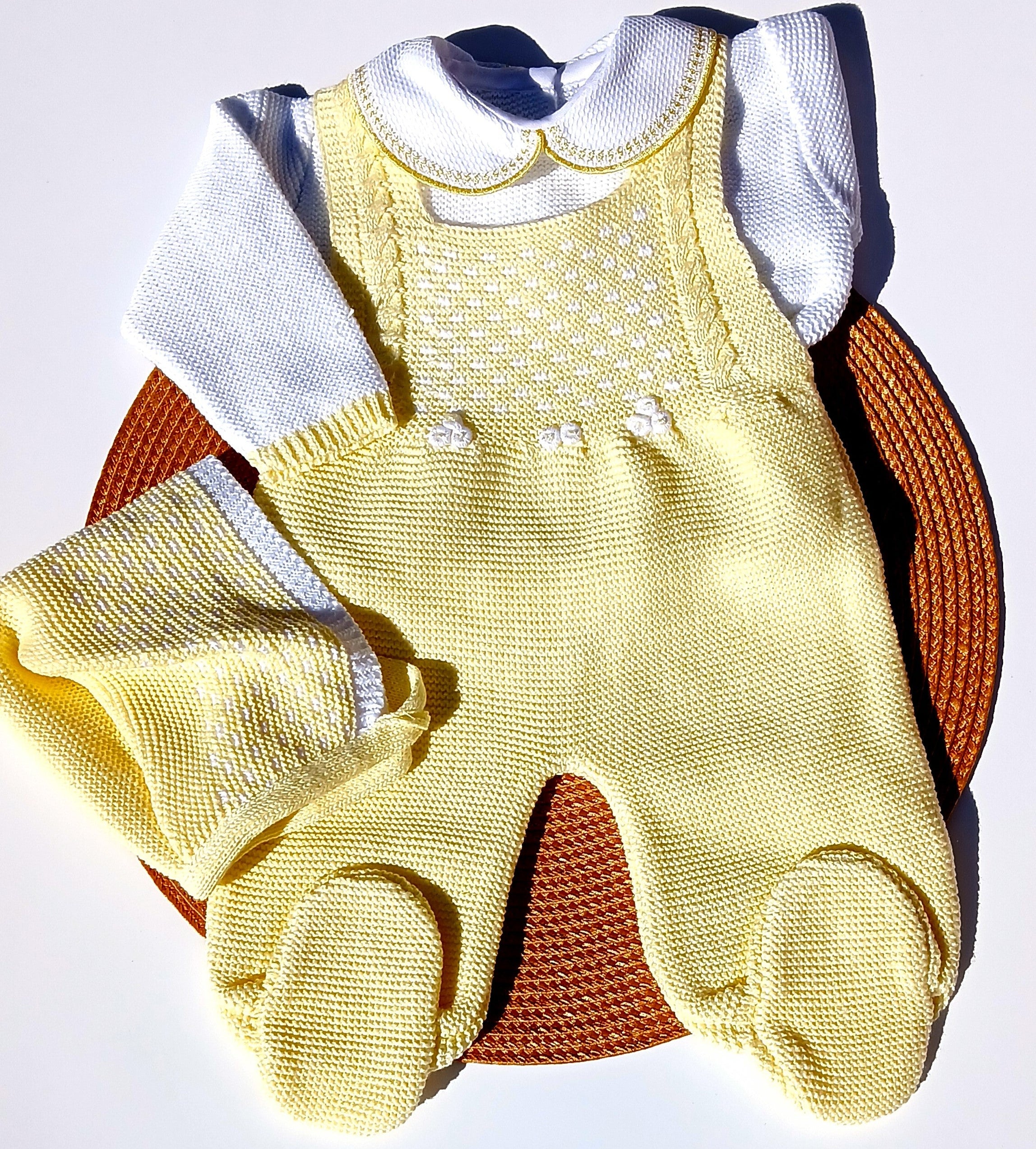 Yellow knitted baby romper with white shirt on a textured surface