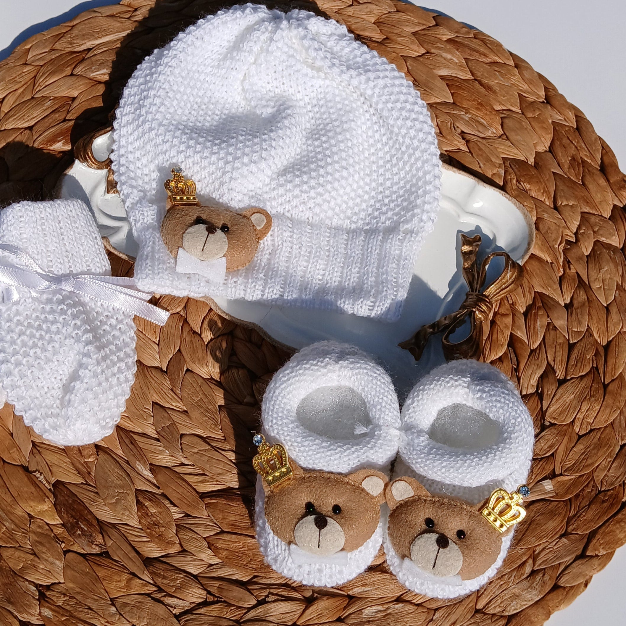 Baby hat and booties with teddy bear design on a woven mat
