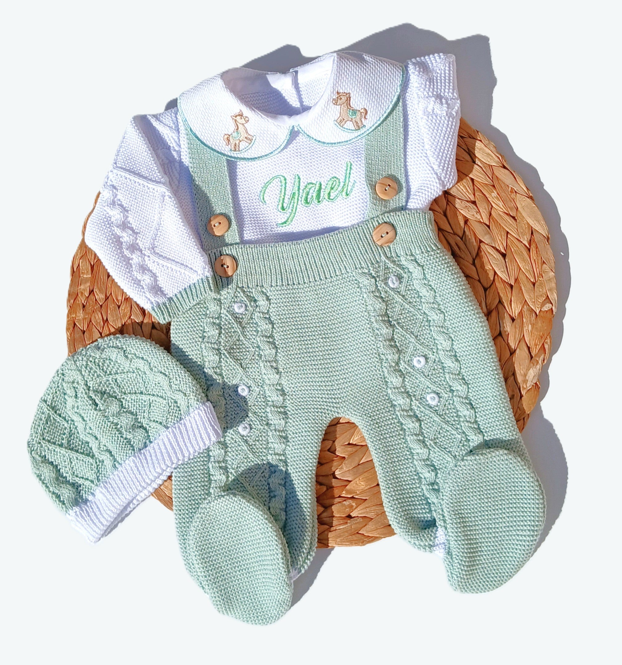 mint green rocking horse Baby outfit with green knitted romper, white shirt, and matching hat on a woven basket.