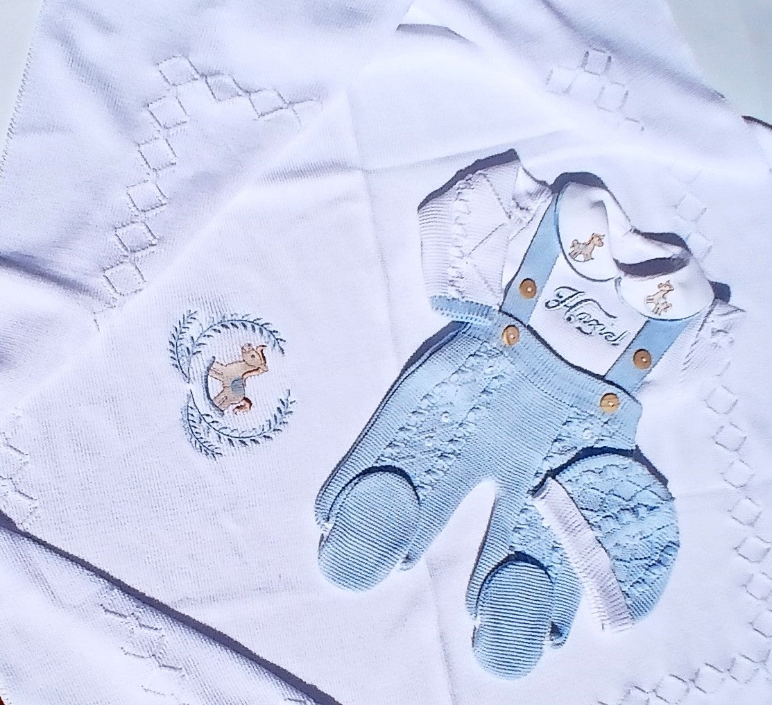 Baby outfit with blue overalls and white shirt on a textured fabric background
