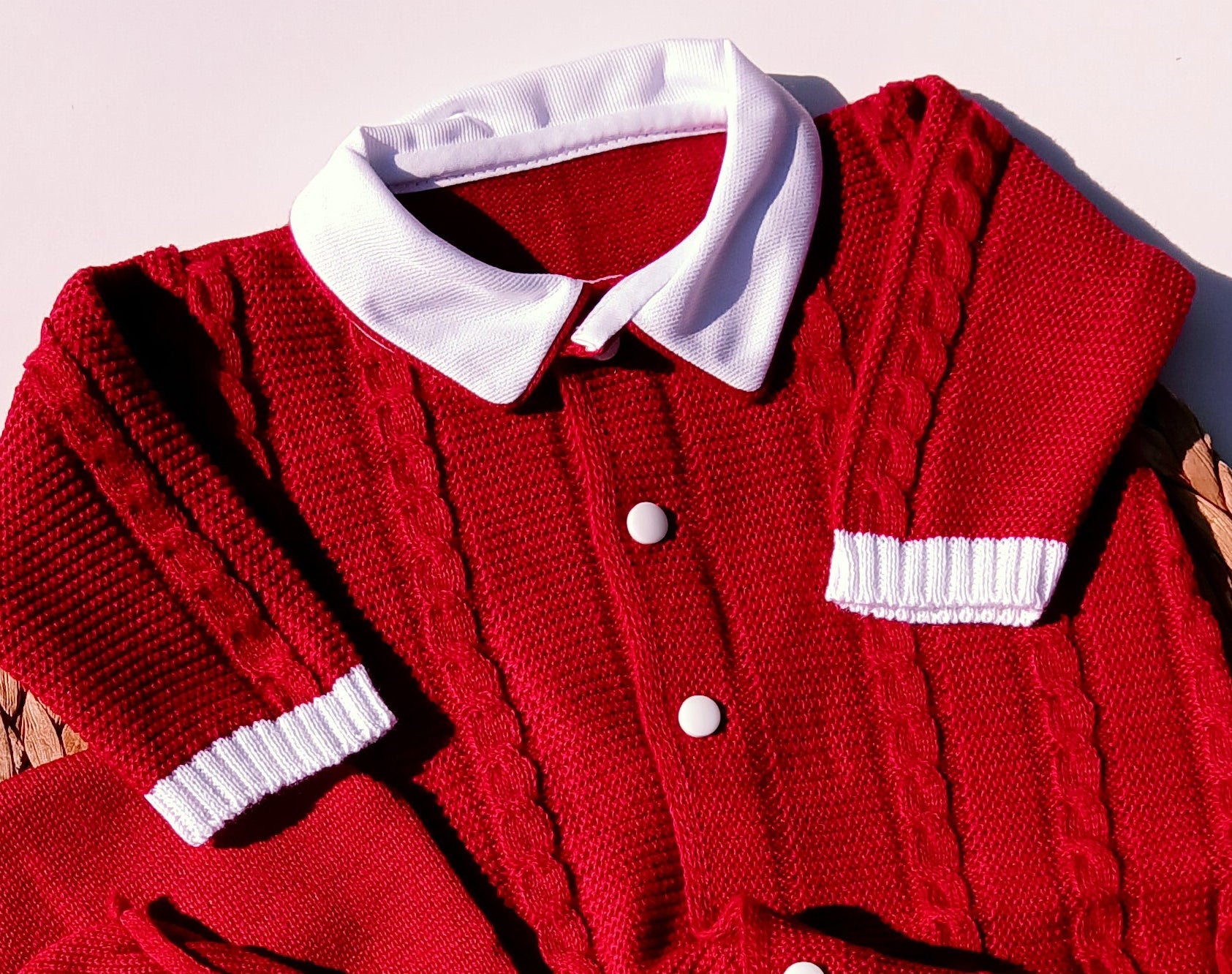 Red jacket with white buttons on a light pink background