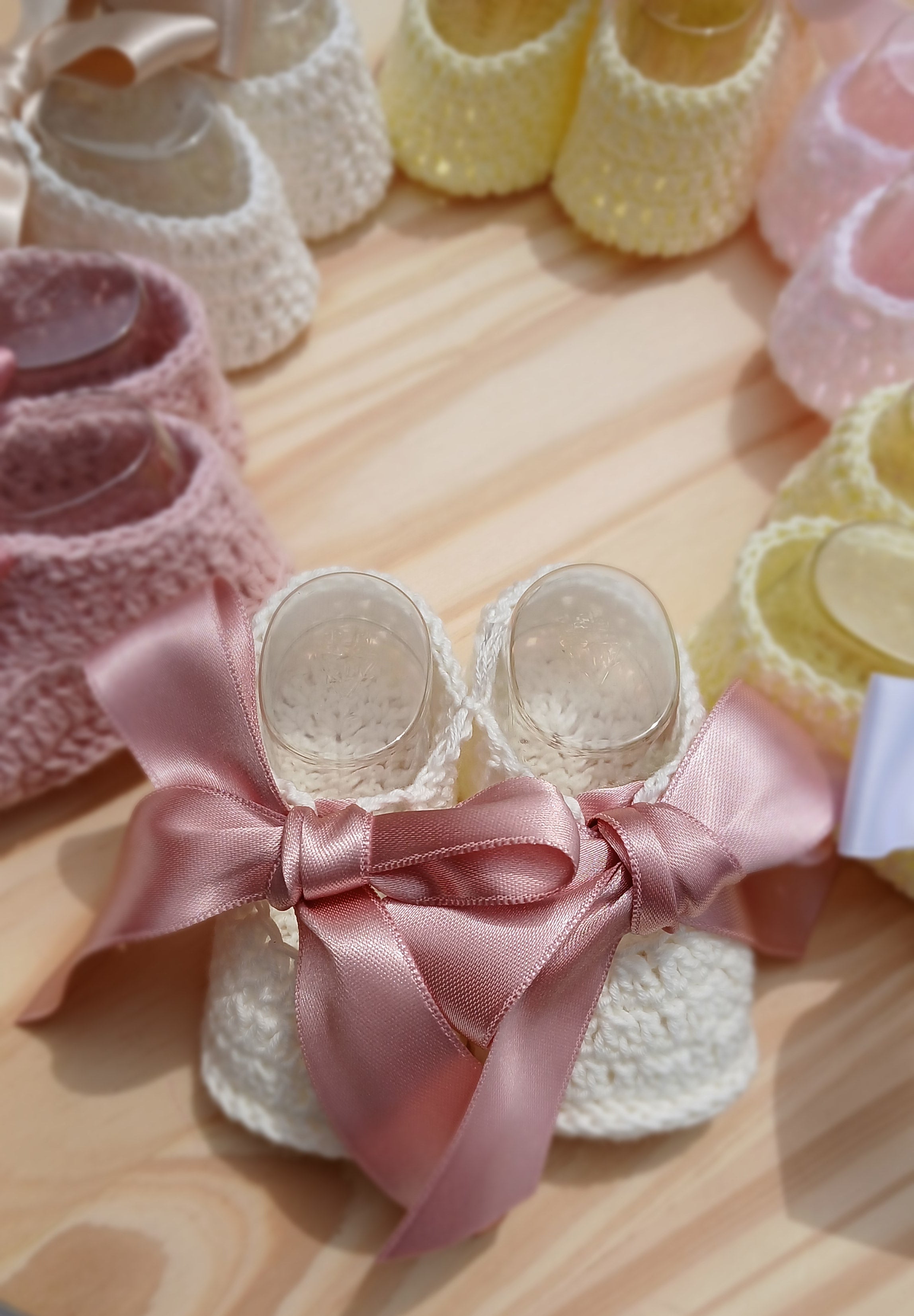 Close-up of a decorative wreath with pink and yellow ribbons on a wooden surface.