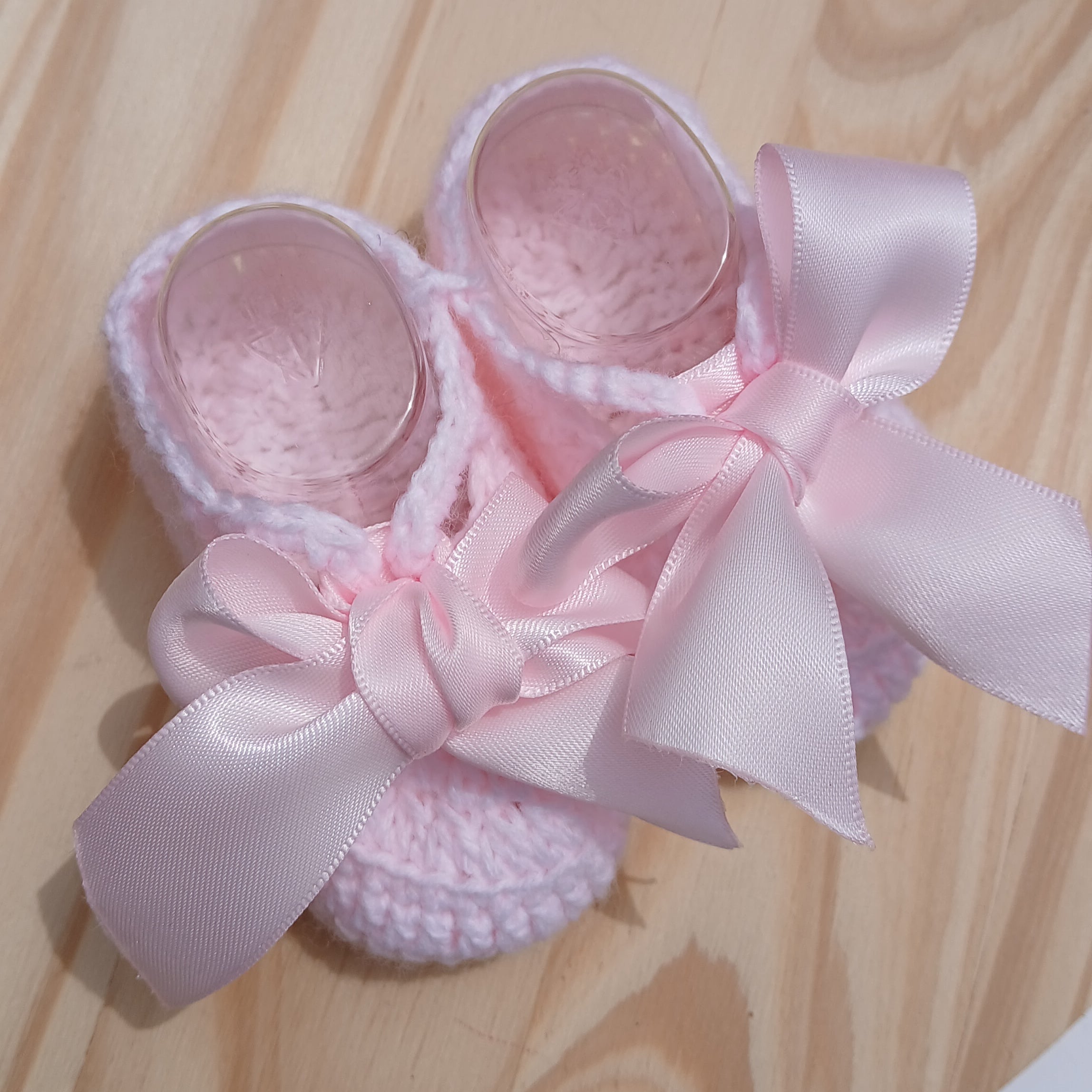 Pink baby shoes with a bow on a wooden surface,  baby Bootie crochet  pink with satin bow 