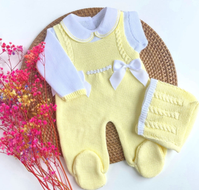 Yellow baby romper with white collar and bow on a woven mat with pink newborn knit going home outfit, newborn baby girl coming home knit outfit flowers.