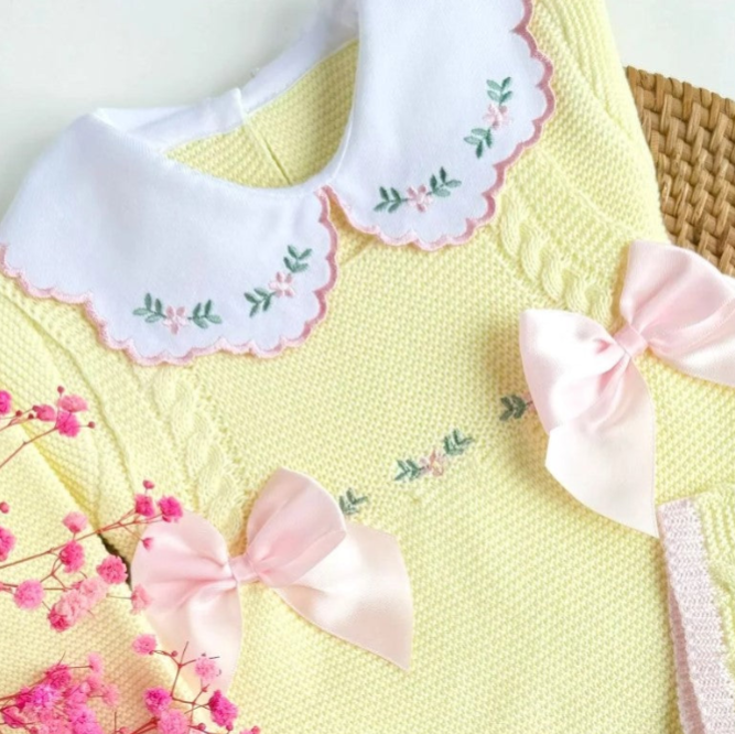 Yellow dress with floral embroidery and pink bows on a white background