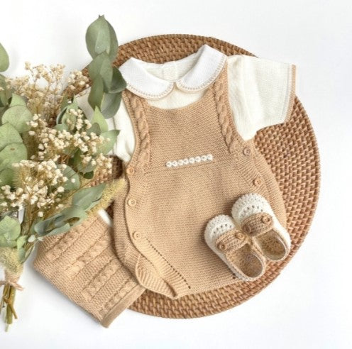 Baby outfit set with knitted romper, white shirt, and shoes on a woven mat with flowers. Baby outfit with pearl Ivory knitted cardigan, pants, and shoes on a woven mat with flowers. newborn summer outfit