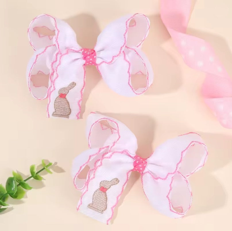 Two large white bows with pink edges on a beige background. white Easter bunny embroidered